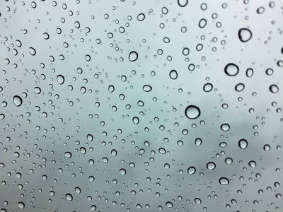 挡风玻璃上的雨滴或挡风玻璃窗上的雨点。从车内看到灰色的天空背景。它可以用于纹理背景或显示或背景