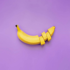 切香蕉, 切片, 在霓虹灯紫色背景上排列的丁.文本空间.简约理念照片