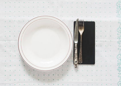白色空盘子与老式银色洁具叉子和刀在圆点 tableclot
