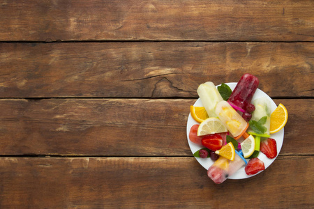 自制五颜六色, 水果冰棒, 新鲜水果在白色的盘子和一个黑暗的木质背景。草莓, 柠檬, 柠檬, 薄荷, 橙, 樱桃, Multif
