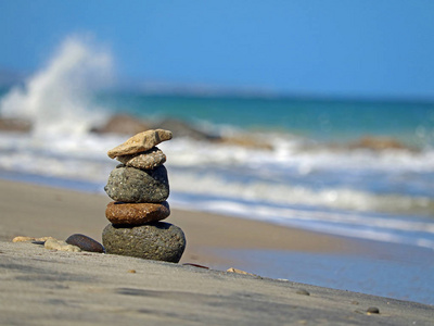 在海滩上的石头炮塔在背景上波浪, 平衡和和谐的概念