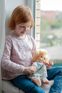 在窗台上玩娃娃的女孩