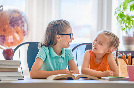 回学校去快乐可爱的勤劳的孩子们坐在室内的书桌旁。孩子们在课堂上学习