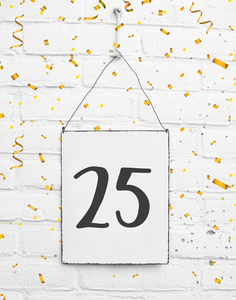 生日聚会卡片文本与金黄纸屑, 数字二十五, 金属板材白色砖背景照片