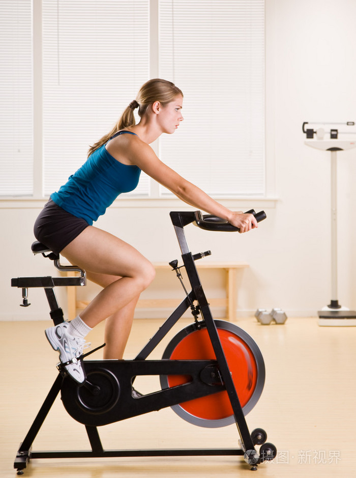 女人骑固定自行车在健身俱乐部