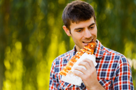 一个年轻男子吃比萨饼的肖像。产品演示徽标和文本的样机。生活方式