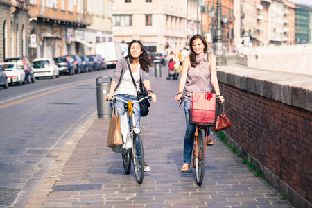 行走在城市与自行车和袋中的两个漂亮女人