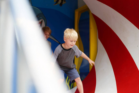 两个小男孩在一个旋转的隧道里玩耍, 因为他们在一个小镇的美国狂欢节上退出游乐场。