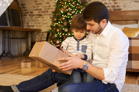 父亲与小儿子打开礼品盒在公寓装饰圣诞节