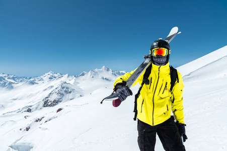 一幅戴着防护头盔和眼镜的滑雪者的肖像, 是在高加索雪山上, 肩上放着滑雪板的面具和围巾。滑雪