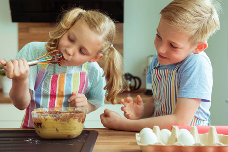两个快乐的孩子在现代厨房的烤松饼中享受巧克力面团的乐趣和味道