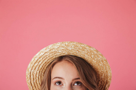 关闭半脸肖像的一个快乐的年轻女子在稻草帽子寻找孤立的粉红色背景