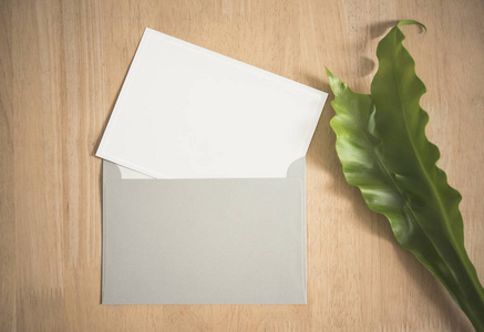 带信封和绿叶的空白白色贺卡。用于样机模板
