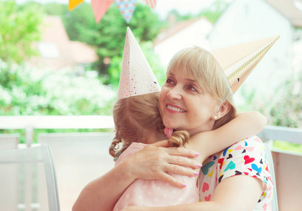 幸福的祖母肖像拥抱她的孙女在她的生日聚会上装饰露台