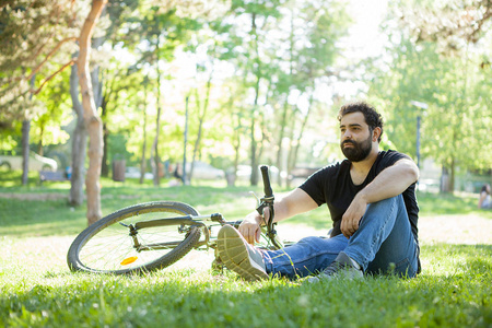 在公园的草地上休息的年轻胡子男子