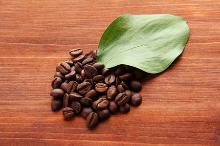 咖啡豆与木制背景上的叶子