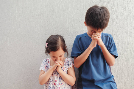 亚洲男孩和女孩闭着眼睛祈祷