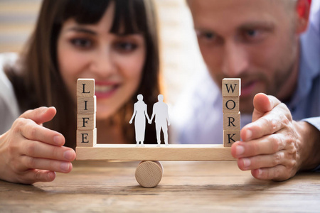 幸福夫妇保护工作和生活之间的平衡与家庭纸削减跷跷板照片