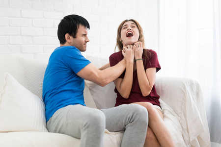 男脖子愤怒的男友试图从背后抓住女人的脖子, 勒死并引起她的痛苦.