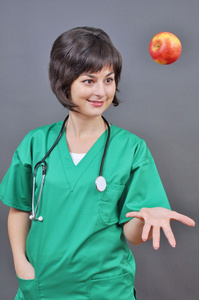 有吸引力的女医生与新鲜苹果灰色背景