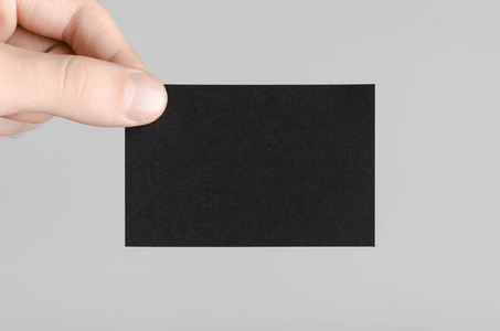 黑色名片模型 85x55mm在灰色背景上持有空白卡的男性手