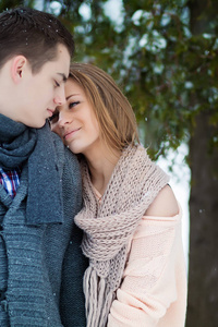 愉快的年轻夫妇拥抱在冬天公园