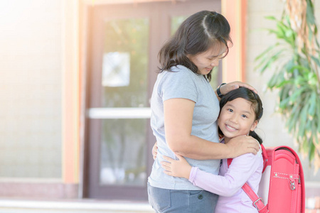 亚洲可爱的学生与 bagschool 拥抱她的母亲在学校, 爱概念