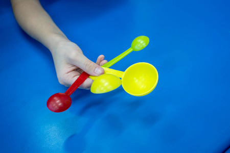 女孩介绍测量勺子设置在蓝色桌的红色和黄色颜色在实验室里