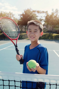 年轻的亚洲男孩网球运动员在室外蓝色法院