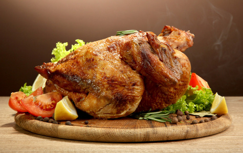 整个烤的鸡配蔬菜 木桌上，棕色背景上