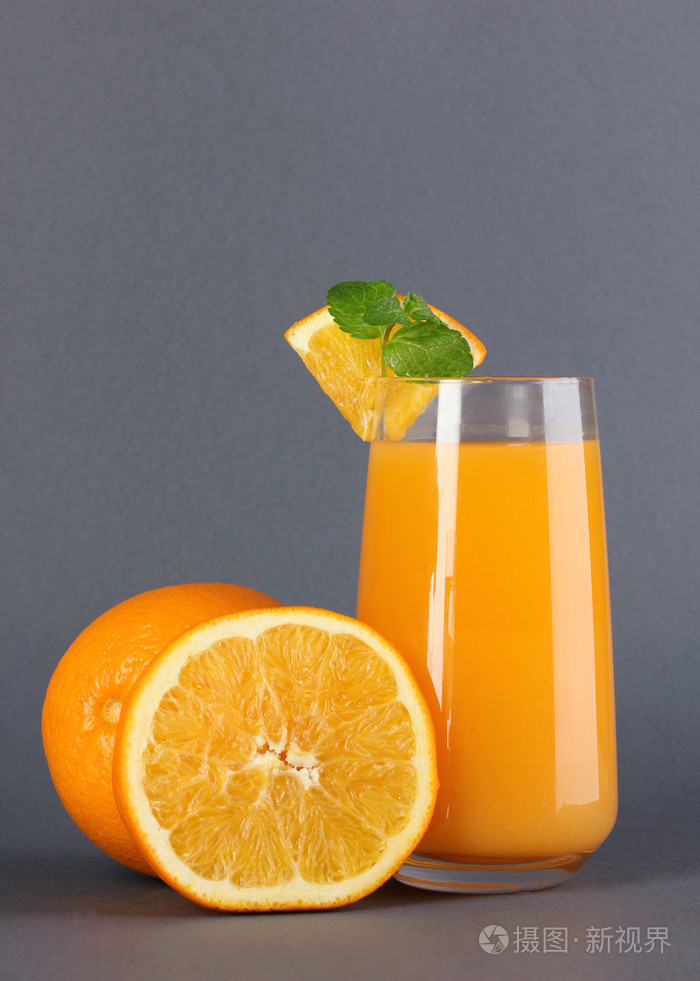 杯橙汁与薄荷和灰色的背景上的橙色
