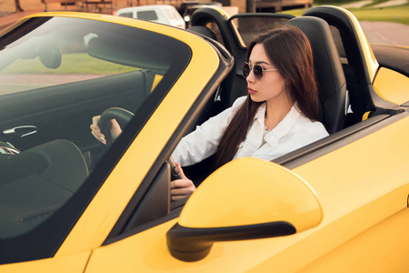 相信自己侧面查看图片的美丽迷人的黑发女郎的年轻女性驾驶黄色敞篷车