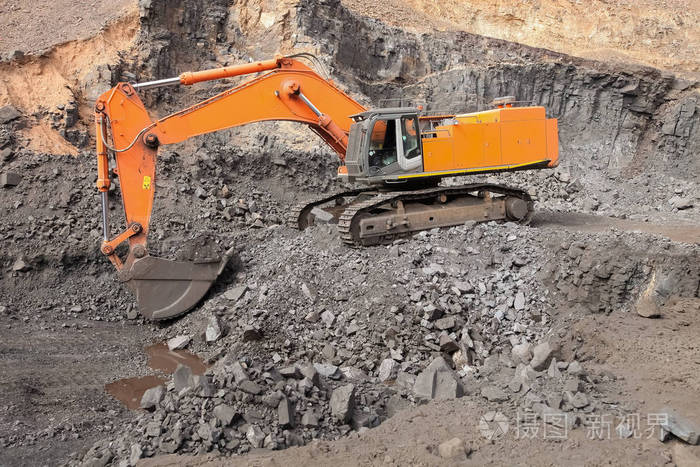 挖掘机挖掘富矿岩并将其装载到岩石转储卡车上进行加工