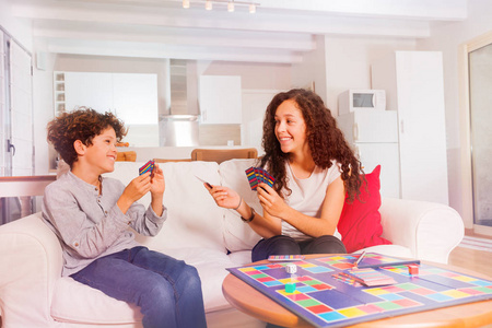 微笑的青少年的肖像, 兄弟和姐妹, 玩纸牌游戏玩的开心, 坐在沙发上在家