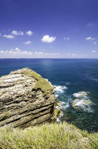 热带海景从悬崖顶部在晴朗的一天. 波浪击中岩石和令人惊叹的岩石海岛以蓝天背景