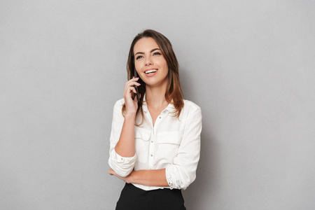 一个微笑的年轻的商业妇女的肖像谈论手机在白色背景下隔离