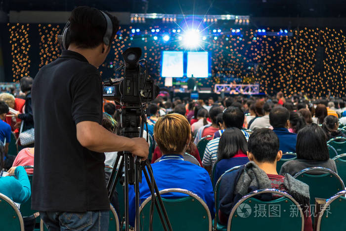 视频摄像师的后侧在舞台上以观众的视角拍摄, 展示中心背景,活动和