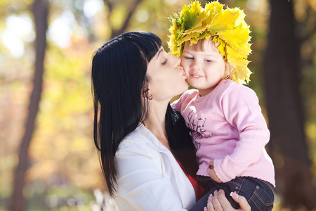 美丽年轻的母亲，她的女儿举行的枫叶花圈