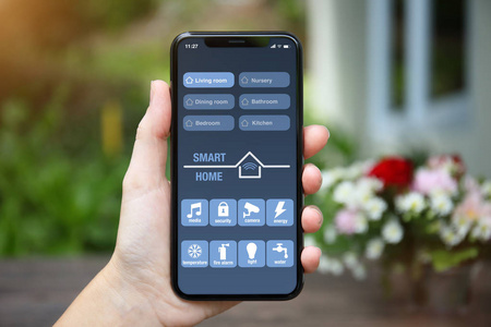 女性手手持手机与 app 智能家居在屏幕背景下的花园别墅