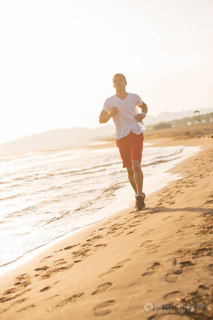 日出时在海滩上奔跑的人的全长视图