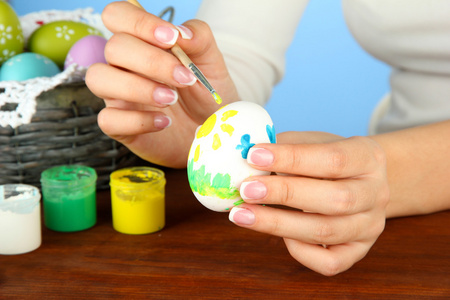 年轻女子绘画颜色背景上的复活节彩蛋