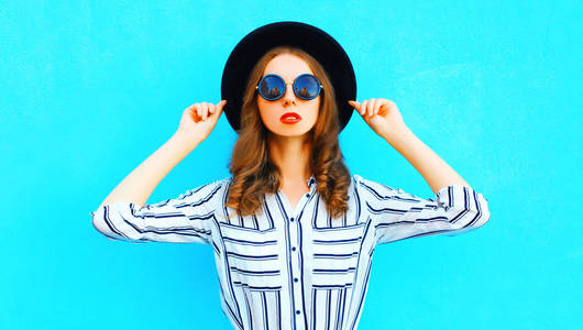 优雅的女人戴着黑色的帽子摆在城市上空彩色蓝色背景