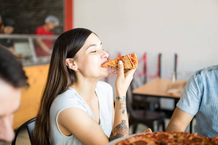 愉快的妇女的画像与朋友享用比萨