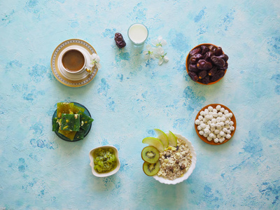 早餐与麦片在绿松石背景。麦片与土耳其糖果, 猕猴桃, 日期和牛奶