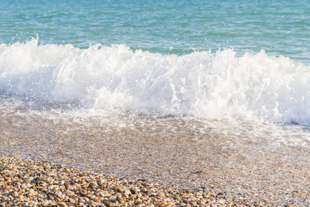 一波在沙滩和卵石海滩上奔跑的海浪