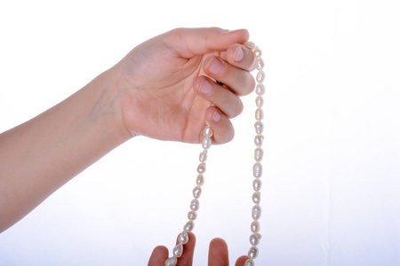 手拿着一串珍珠项链，白色背景上
