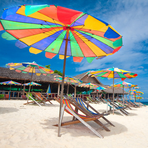 田园诗般的热带岛屿度假与日光浴床和阳伞在白色的沙滩上