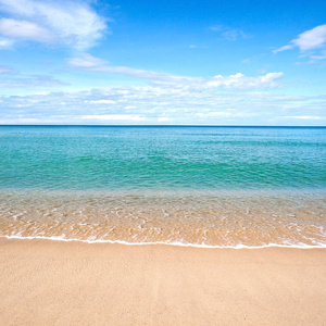 美丽的海滨沙滩与平静水对蓝蓝的天空照片