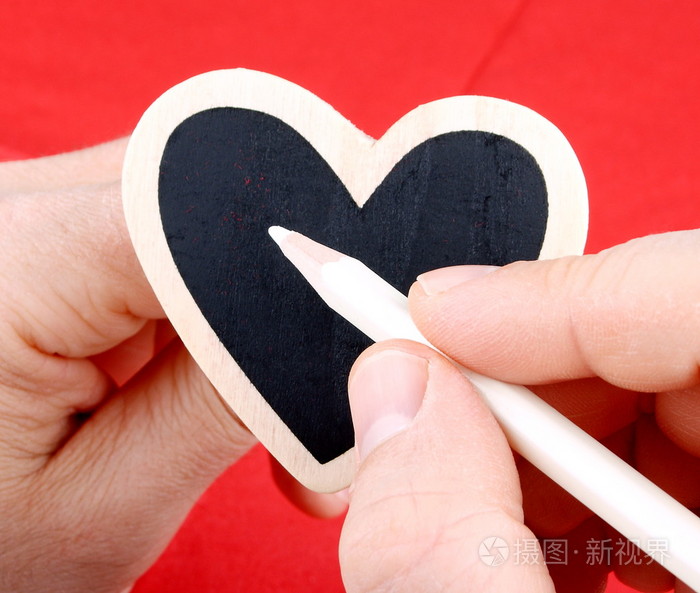 在红色的背景上刻有白色粉笔的手中的心