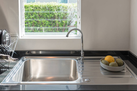 水槽与厨房的水龙头，现代计数器与接收器在厨房里，室内设计概念